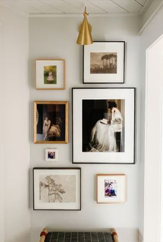 a wall with many pictures on it and a bench in front of the photo frame