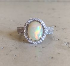 an opal and diamond ring sits on a table