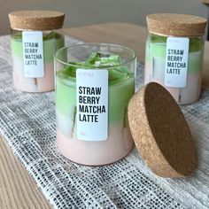 three small candles with labels on them sitting on a table next to a cork lid