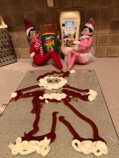 the elf is sitting on the counter next to some candy and other items in the kitchen