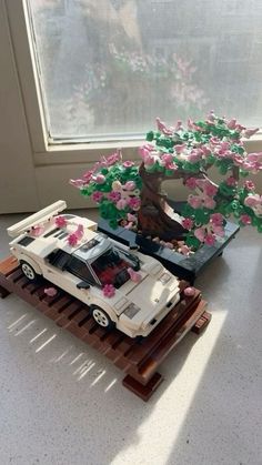 a toy car is parked in front of a tree with pink flowers on the trunk