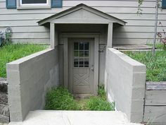 an outhouse built into the side of a house with grass growing in front of it