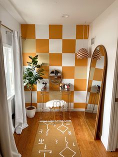 an orange and white checkered wall in a small room with a mirror, stools, rug and potted plant