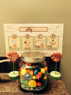 a glass jar filled with candy sitting on top of a counter next to a sign