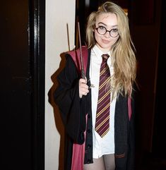 a woman dressed in harry potter costume holding two wands and posing for the camera