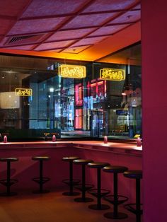 the interior of a restaurant with neon lights and bar stools in front of it