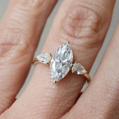 a woman's hand with a diamond ring on top of her finger and an engagement band