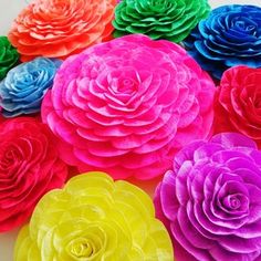 colorful paper flowers are arranged on a white surface