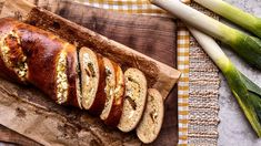 a loaf of bread sitting on top of a wooden cutting board next to celery stalks