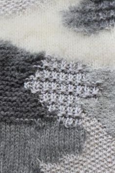 a close up of a knitted piece of cloth with white and gray designs on it