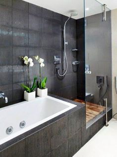 a bathroom with a tub, shower head and flowers in vases on the counter