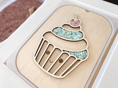 a wooden brooch with a cupcake design on it's side in a box