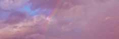 an airplane flying in the sky with a rainbow behind it and clouds above them,