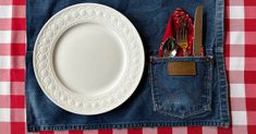 a white plate and fork in a pocket on a red checkered table cloth with utensils