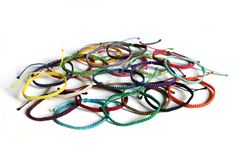 a pile of colorful bracelets sitting on top of a white table next to each other