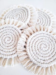 three white round rugs with tasselled ends on a white tablecloth background