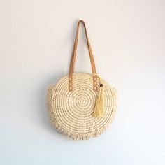 In Stock Fast Shipping From Los Angeles Carry your essentials in sweet, summery style with this Straw Circle Tote Handbag from Elena Handbags. This chic circular bag makes a great option for your warm weather errands like the farmer's market or thrifting, boasting an open-top design that provides quick and easy access to items inside. Double faux leather shoulder straps with whipstitch detailing add more texture to the look, while also providing comfortable carry over your shoulder as you go abo Casual Fringe Beach Bag For Daily Use, Spring Fringe Shoulder Bag For Everyday, Casual Fringed Beach Bag, Spring Travel Bags With Fringe, Casual Everyday Bag With Tassels, Summer Beige Tassel Shoulder Bag, Trendy Crochet Travel Bag With Tassels, Beige Tassel Shoulder Bag For Beach Season, Spring Bohemian Beach Bag With Leather Handles