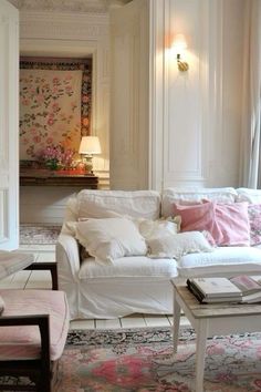 a living room filled with white furniture and lots of pink pillows on top of it