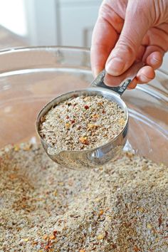 a person scooping spices into a glass bowl