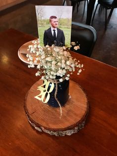 a wooden table with a card and flowers in it on top of a tree stump