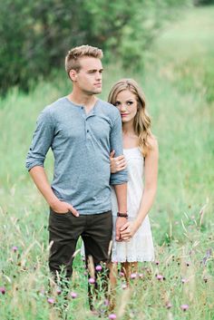 a man and woman standing in tall grass