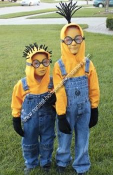 two children dressed in yellow and blue overalls standing next to each other on grass