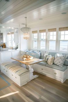 a room with white walls and wooden floors has a bench in the center, windows on both sides