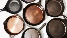 several frying pans lined up on top of each other in different sizes and colors