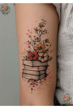 a woman's arm with flowers and books tattoo on the back of her leg