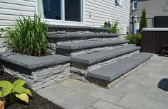 the steps are made out of stone and have plants growing on them in front of the house