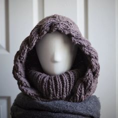 a white mannequin head wearing a knitted scarf and cowl wrap around it's neck