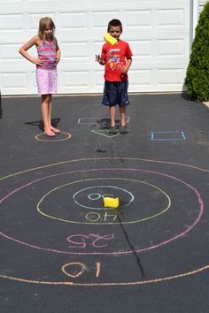 two children standing in front of a driveway with chalk drawings on it