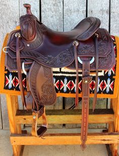 a brown saddle sitting on top of a wooden bench