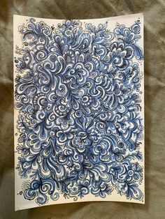 a blue and white paper with swirls on it sitting on top of a bed