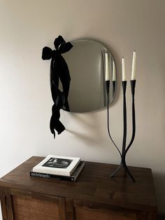 a table with a mirror and two candles sitting on top of it next to a book