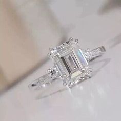 an emerald cut diamond ring with three baguets on the side and two diamonds in the middle