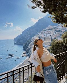 a woman leaning on a railing looking at the ocean