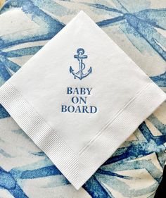 a napkin with an anchor on it sitting on top of a blue and white table cloth