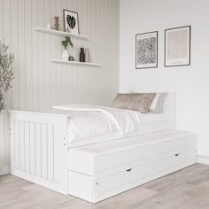 a white bed sitting on top of a hard wood floor next to a wall mounted shelf