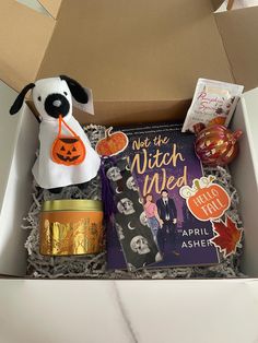 an open box with a stuffed dog in it and some books on the table next to it