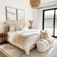 a large white bed sitting in a bedroom next to a window with black framed windows