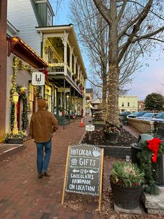 a man is walking down the street in front of some buildings with christmas decorations on them