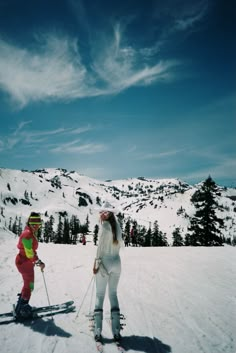 two people on skis in the snow with mountains in the backgrouund