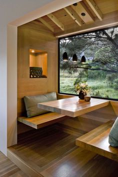 a wooden table and bench in front of a large window