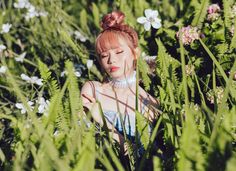 a woman with red hair standing in tall grass