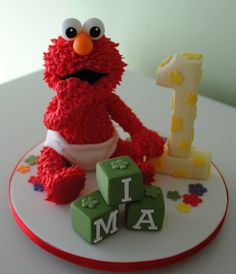 a birthday cake with the number one on it and an elmo figure next to it