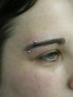 a close up of a person's face with piercings on their forehead and eyebrows