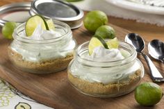 two mason jars with limes and whipped cream in them on a cutting board next to spoons