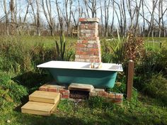 an old bathtub in the middle of a field with steps leading up to it