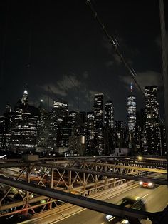 the city skyline is lit up at night, with cars driving on the road below